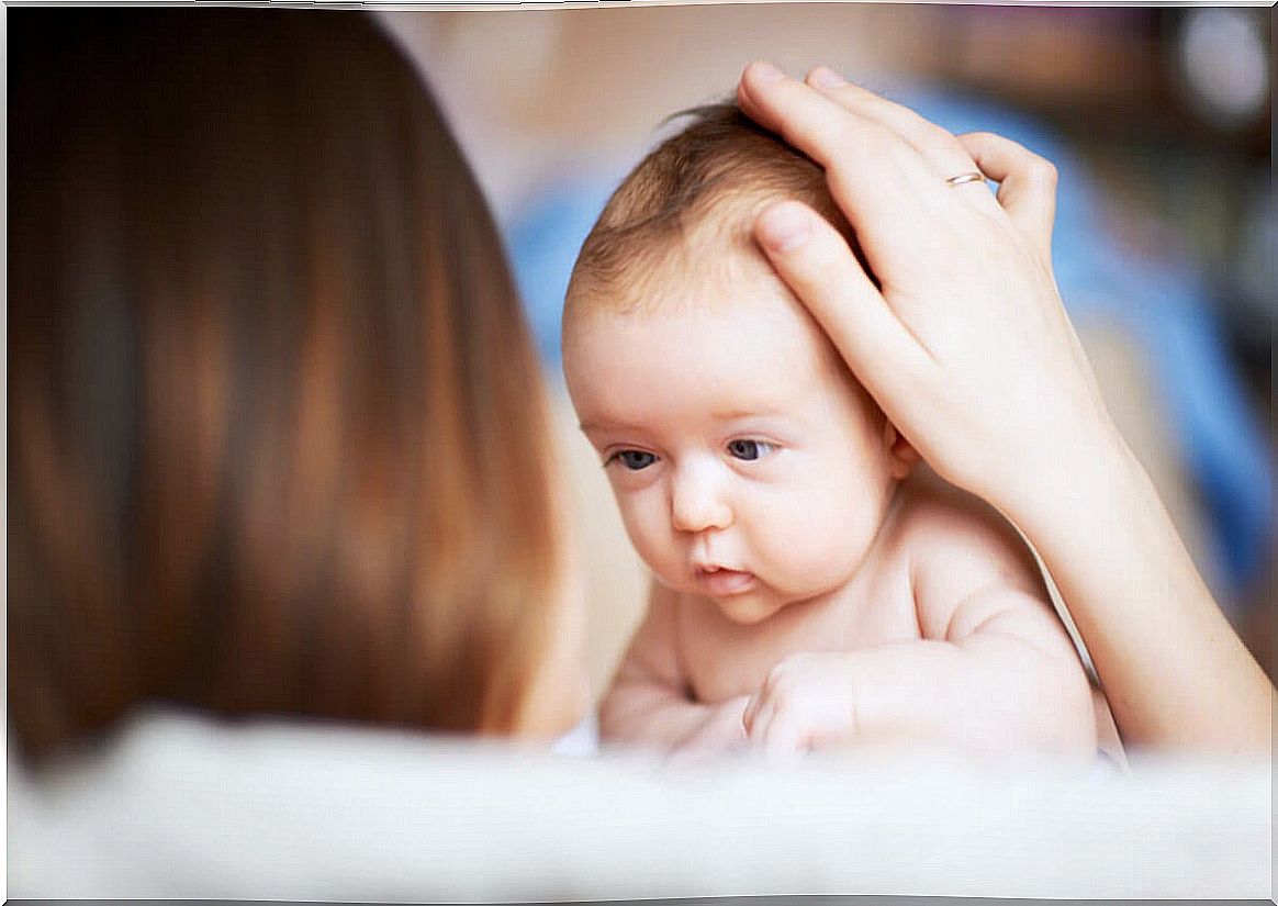 Mom stroking baby on the head.